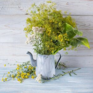 Summer still life with fresh dill, rudbeckia and tomatoes in an old jug.